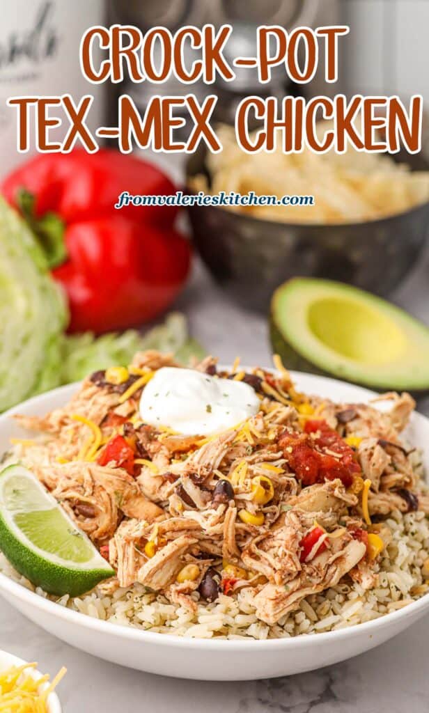 Shredded Tex-Mex chicken on rice with sour cream in a white bowl with a lime wedge with text.
