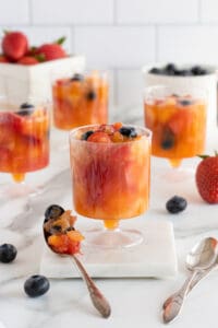 A spoon resting near plastic cups filled with slushy frozen fruit.