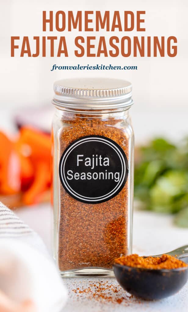 A spice bottle with a label that reads Fajita Seasoning and filled with brown spice next to a measuring spoon full of the spice with text.