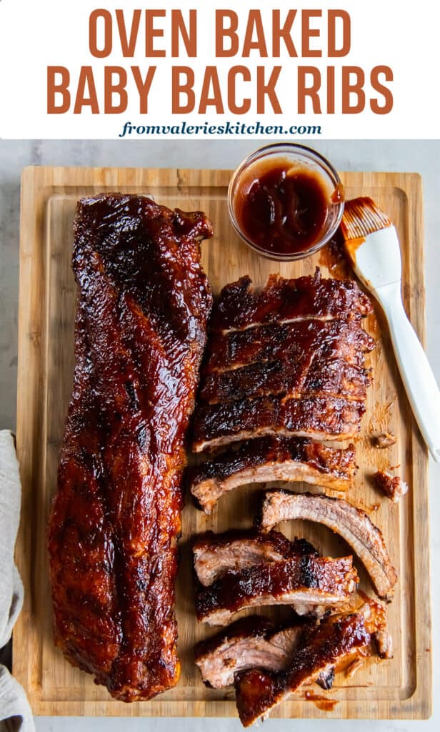 Two racks of baby back ribs on a wood cutting board with bbq sauce and a pastry brush with text.