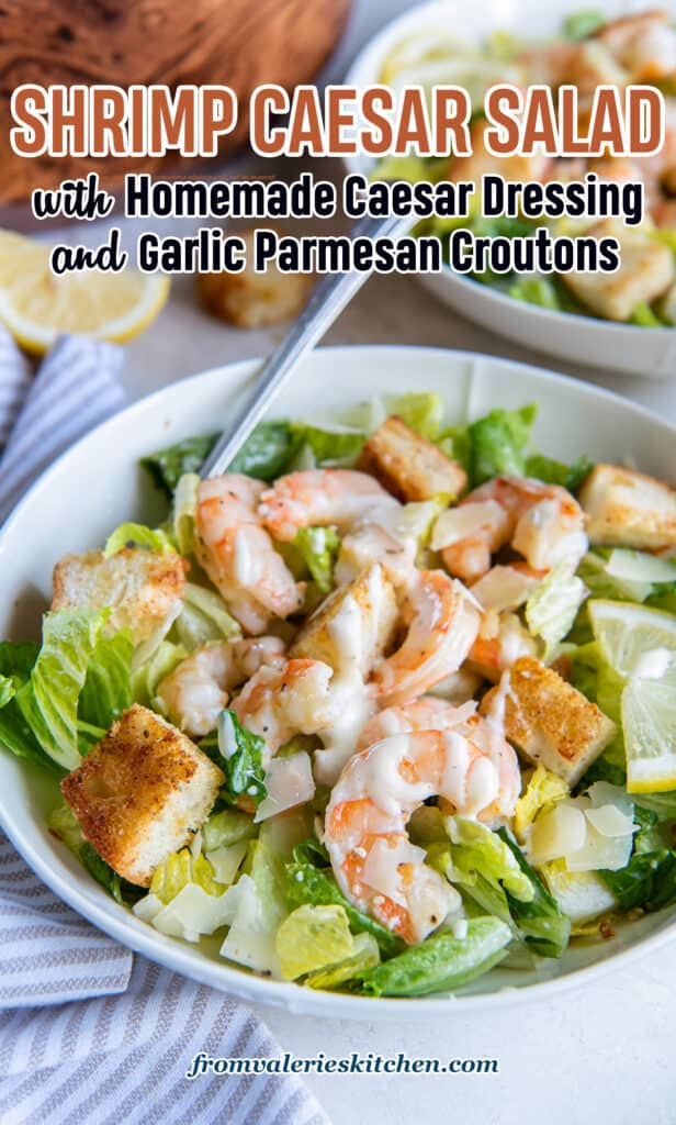 A Caesar salad with shrimp topped with parmesan and croutons in a white bowl with a fork with text overlay.