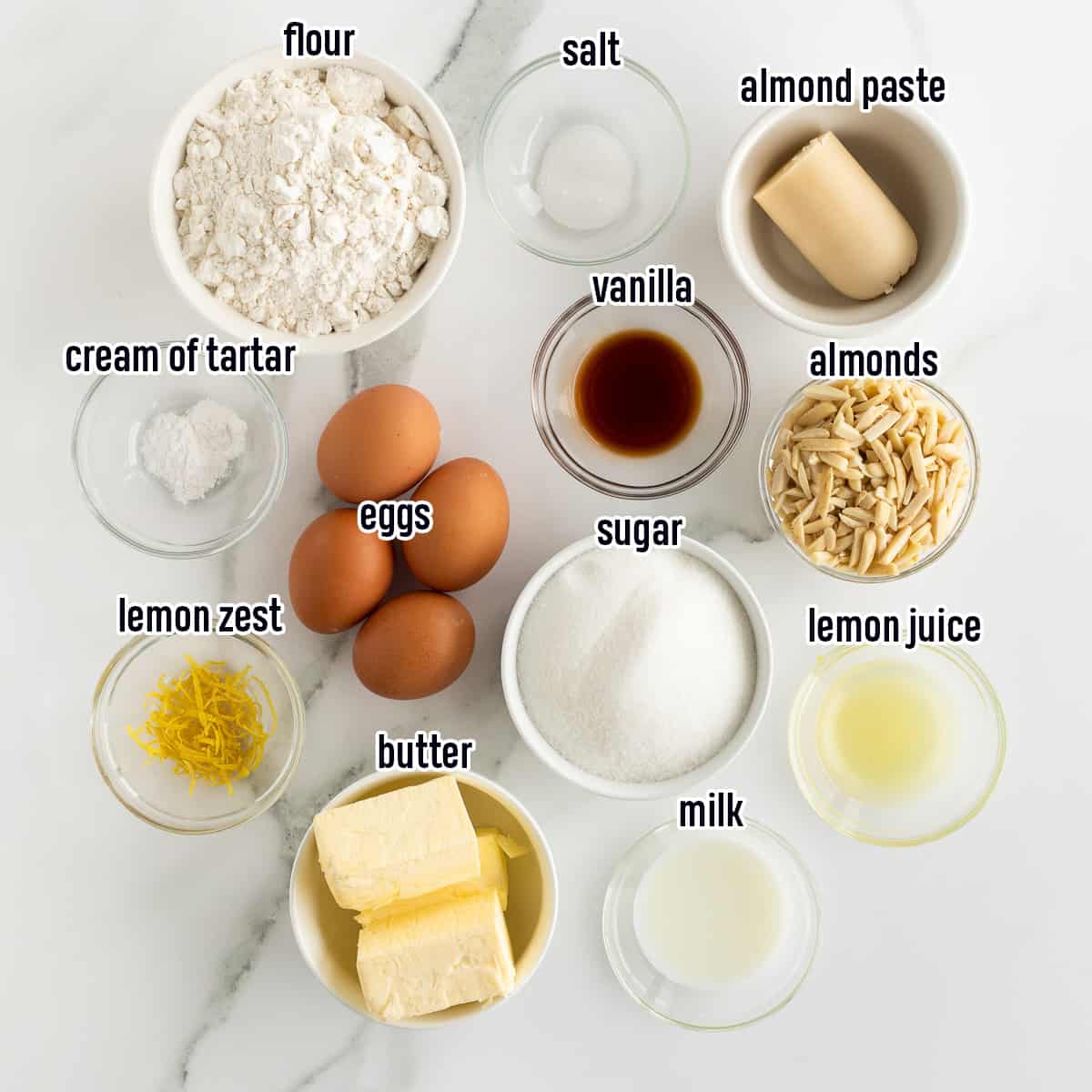 Flour, almond paste, and other cake ingredients in bowls with text.