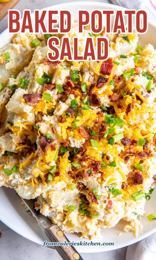 A top down shot of a spoon resting in a bowl of potato salad with cheese and bacon with text.