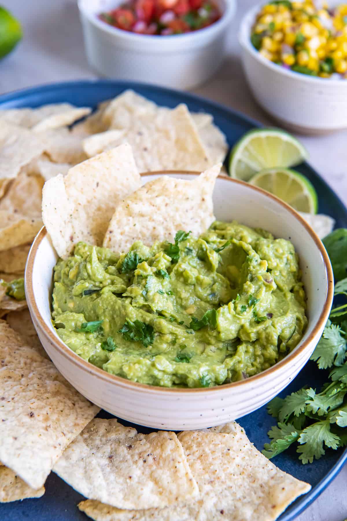 Two tortilla chips pressed into guacamole in a white bowl.