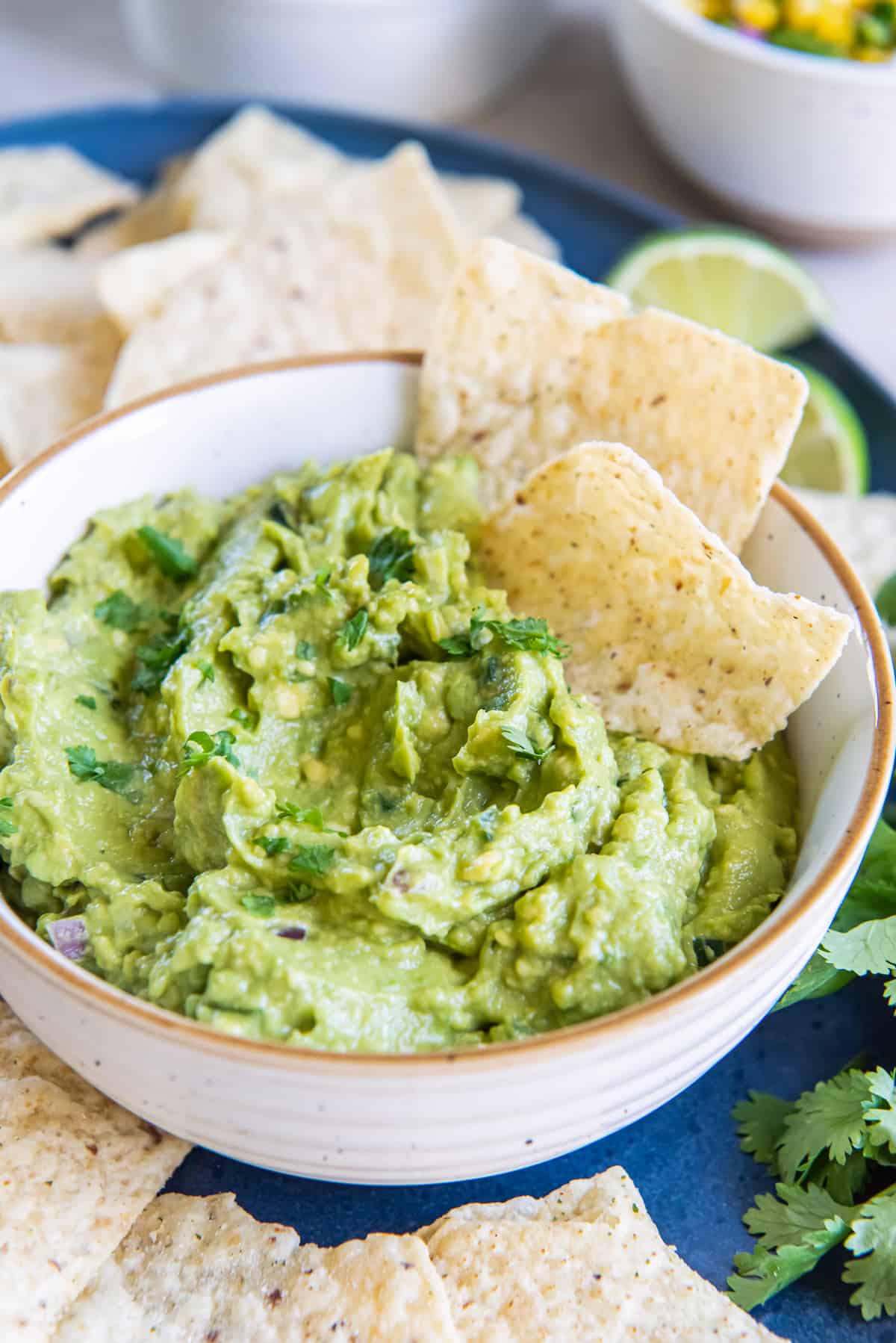 Two tortilla chips pressed into guacamole in a white bowl.