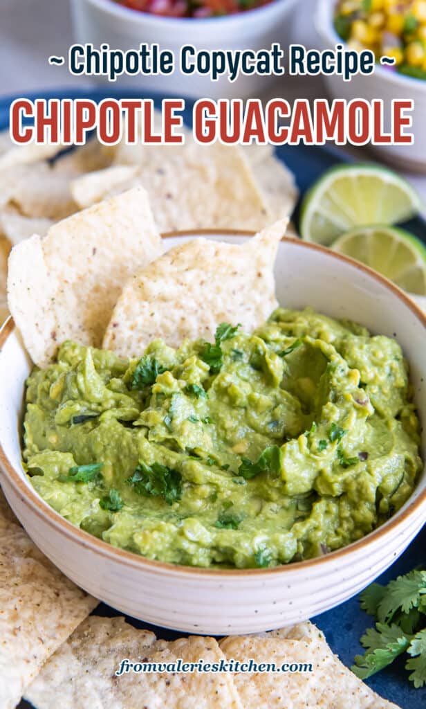 Two tortilla chips pressed into guacamole in a white bowl with text.