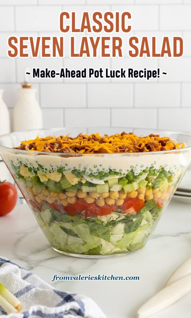 A side view of a glass trifle dish filled with layered salad on a kitchen counter with text.