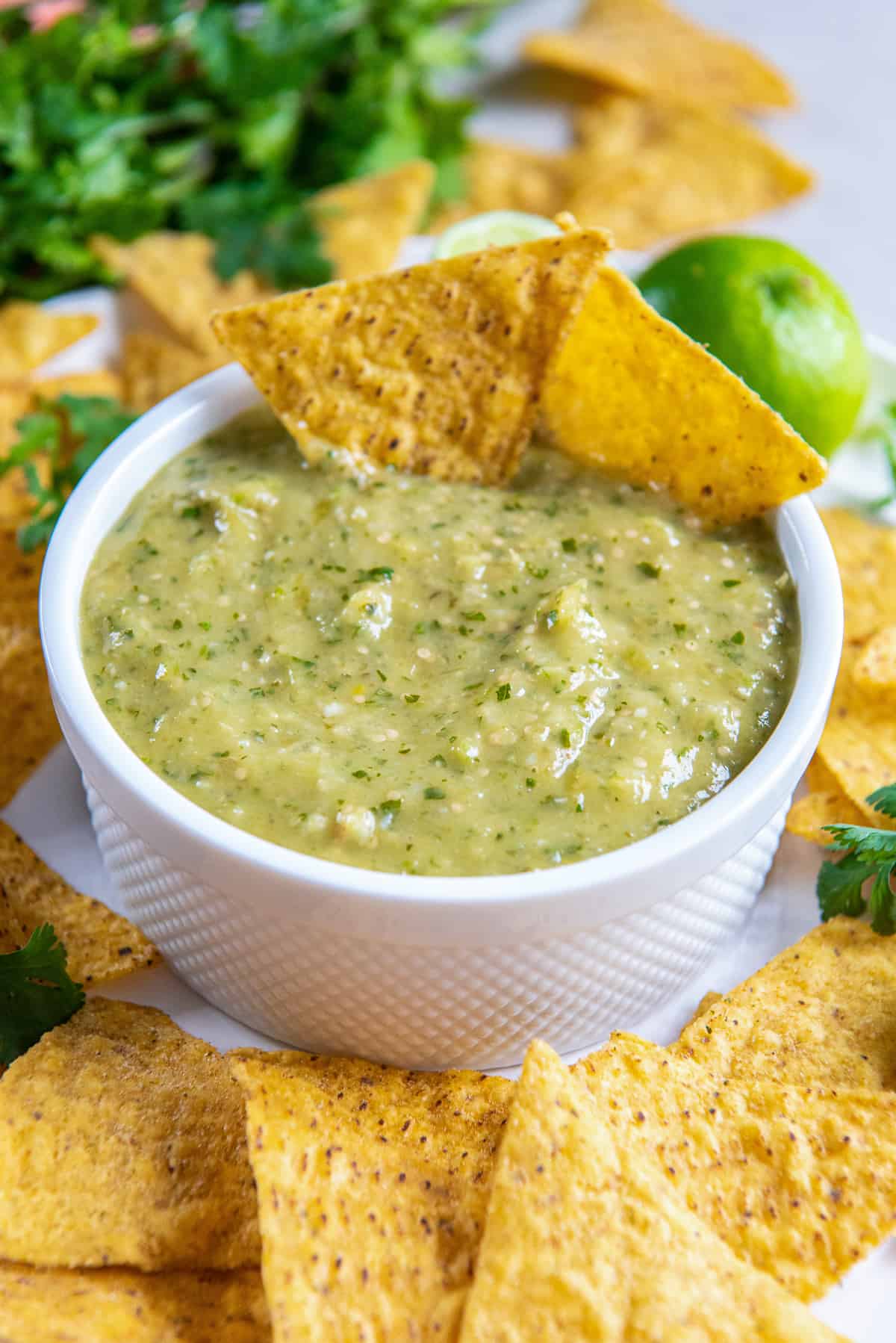 Two tortilla chips resting in a small bowl of tomatillo green salsa.