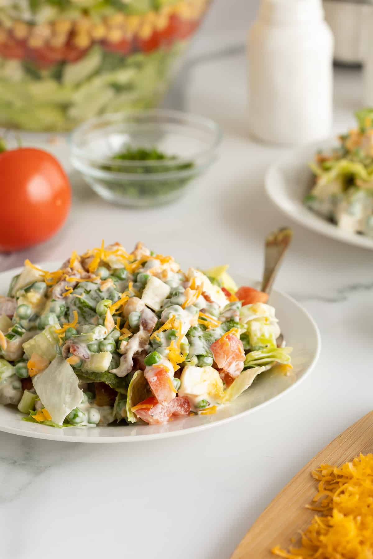 A serving of salad with creamy dressing on a plate with a fork.
