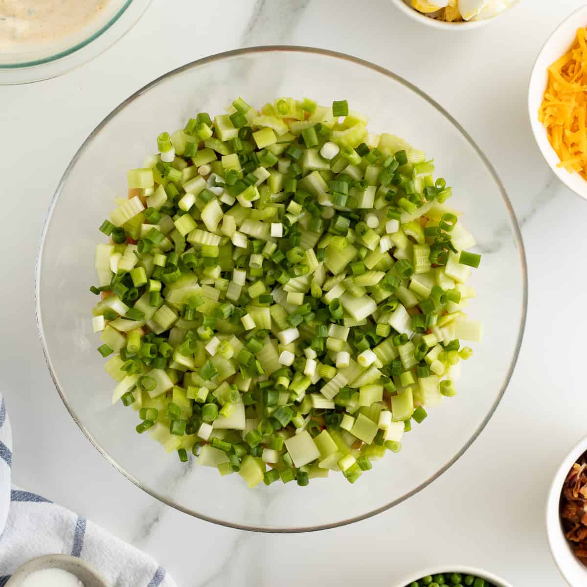 A layer of celery and green onions in a glass bowl.