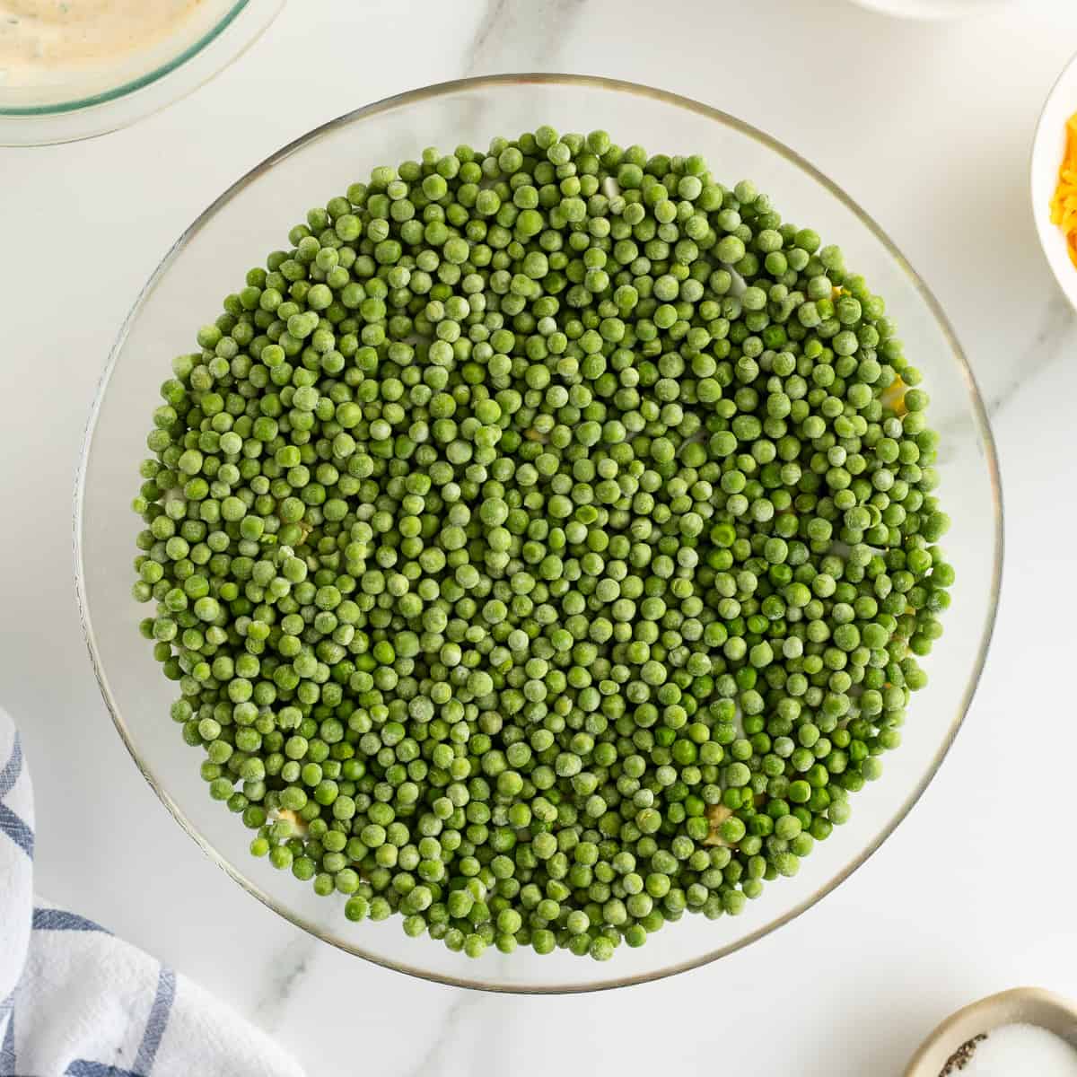 A layer of frozen peas in a glass bowl.