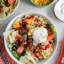 Two bowls of taco salad topped with Catalina dressing and sour cream.