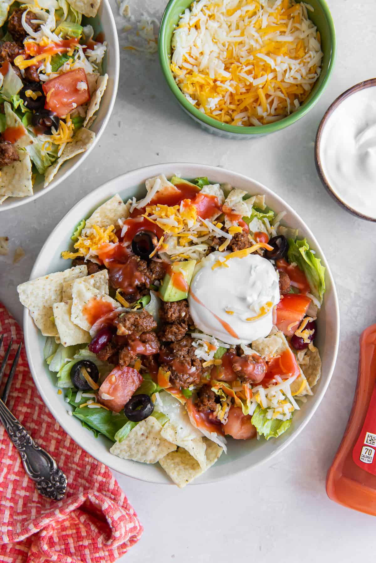 Two bowls of taco salad topped with Catalina dressing and sour cream.