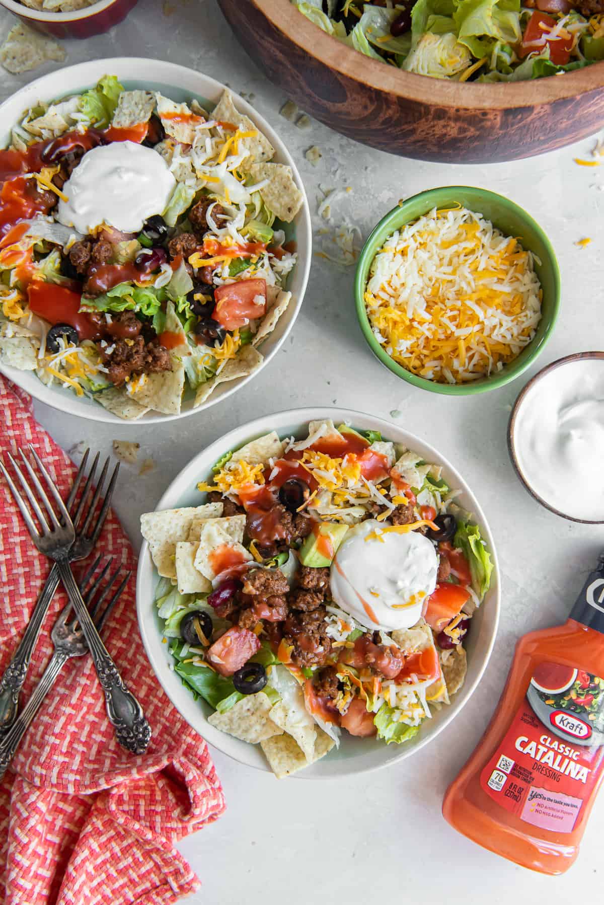 Two bowls of taco salad topped with Catalina dressing and sour cream.