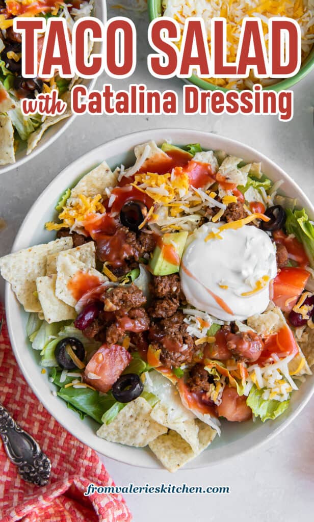 A bowl of taco salad topped with Catalina dressing and sour cream with text.