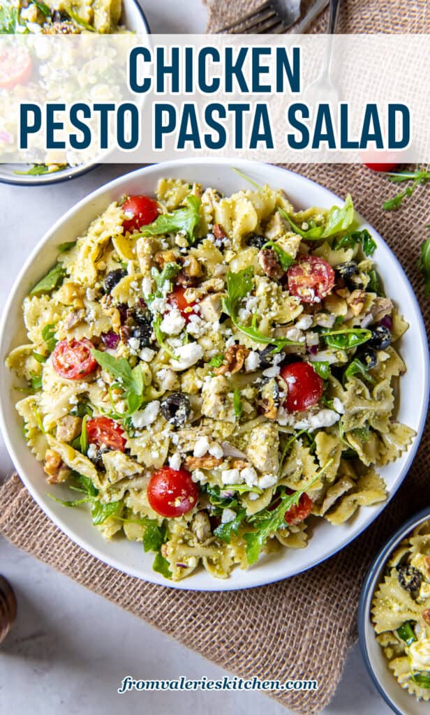 A top down shot of a large serving bowl filled with chicken pesto pasta salad next to two small serving bowls with text.