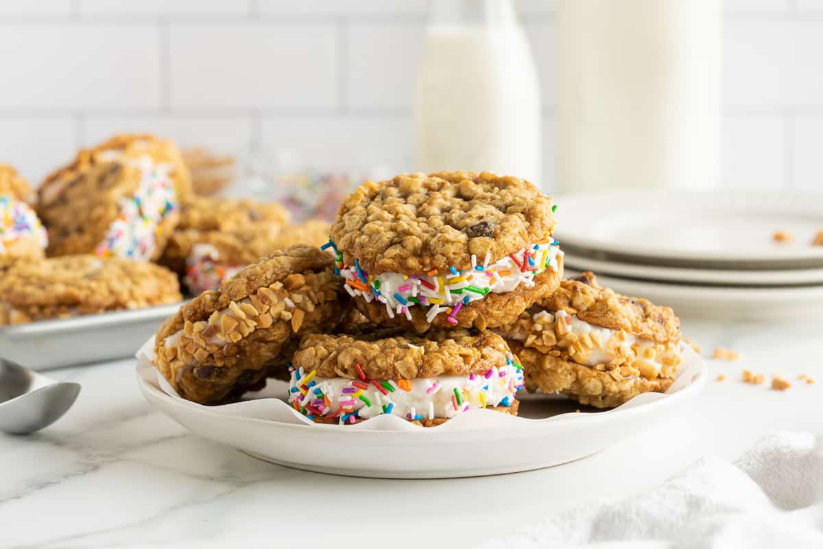 Cookie ice cream cookie sandwiches stacked on a white plate.