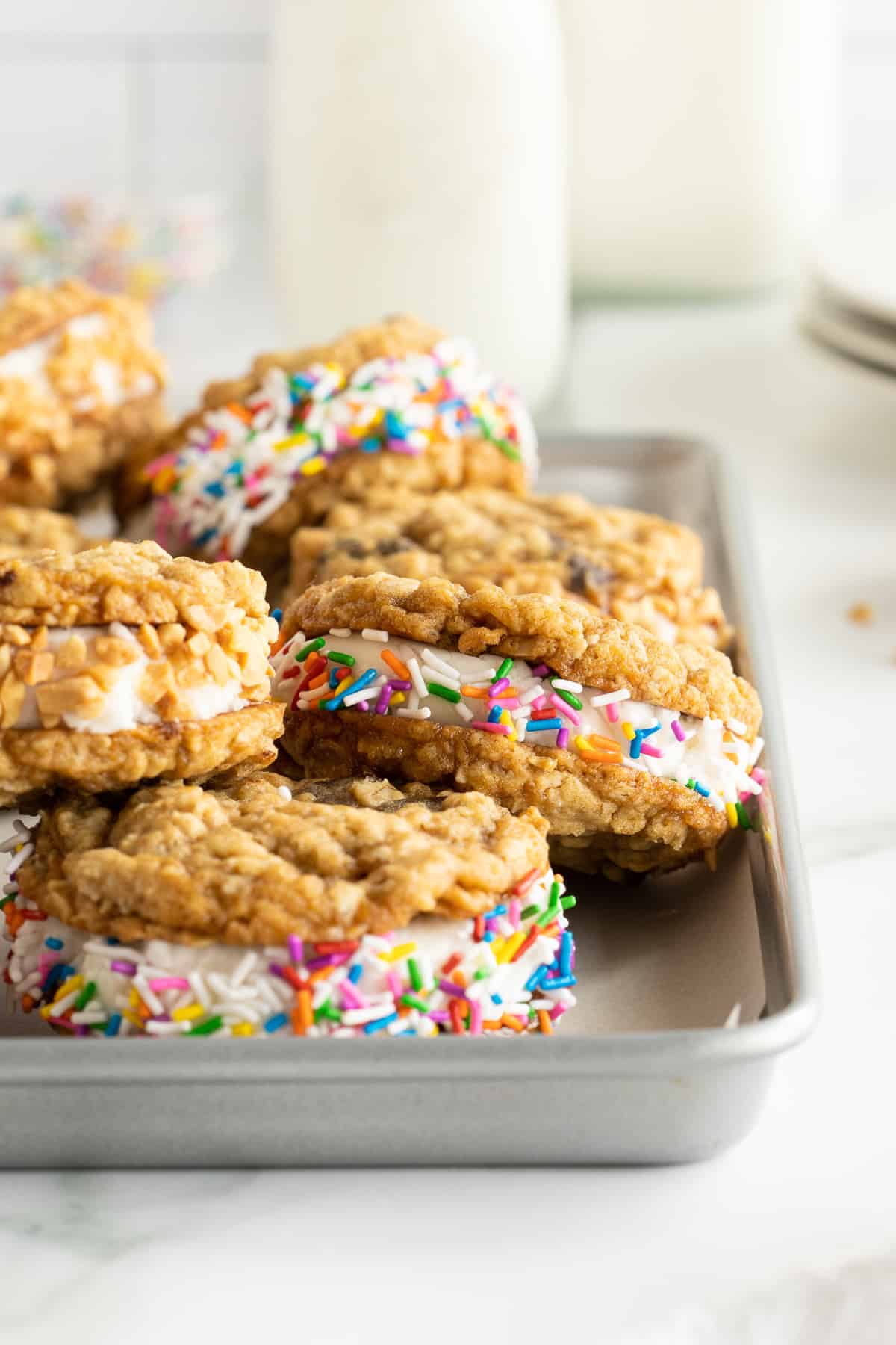 Cookie ice cream sandwiches stacked on a baking sheet.