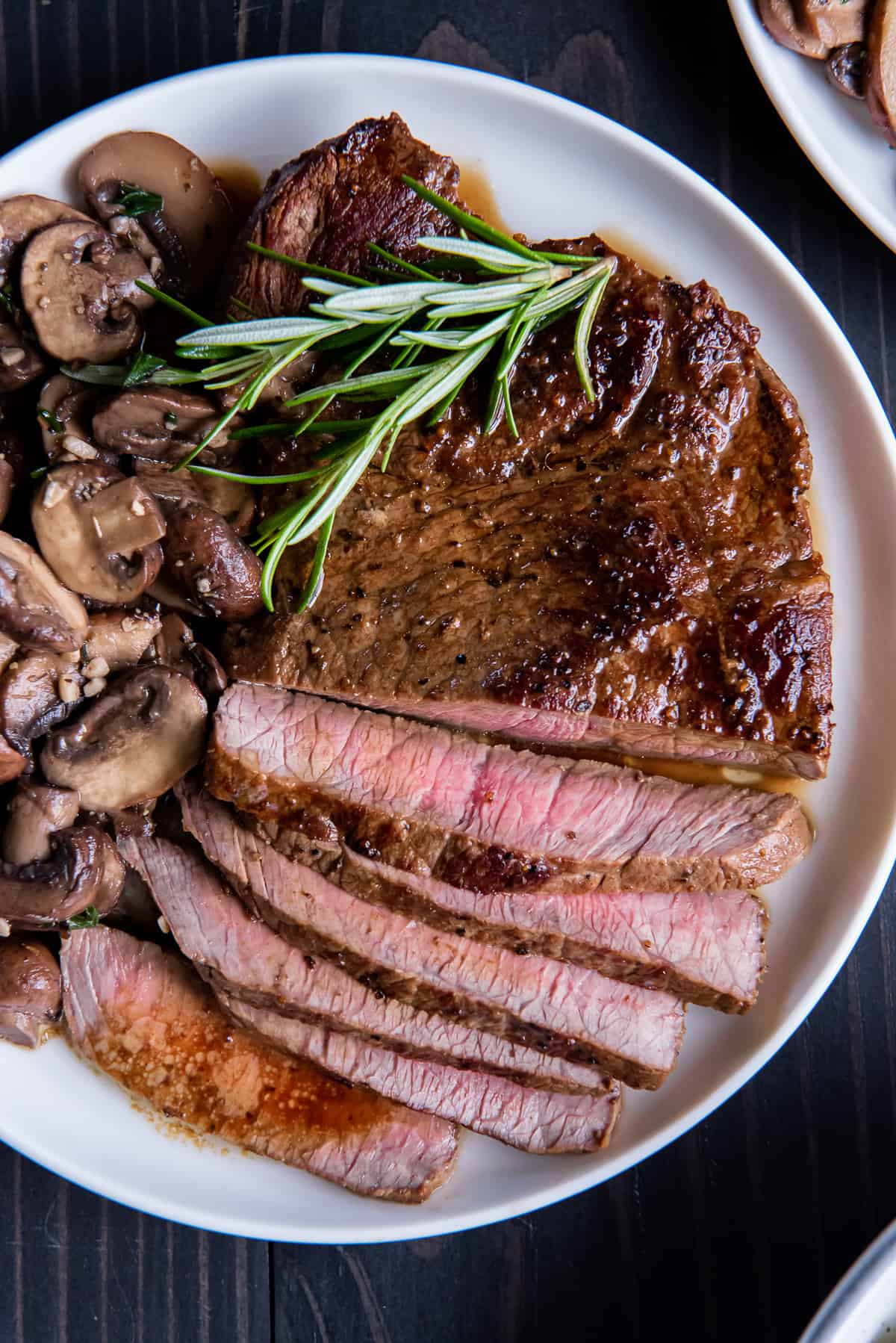 A top down shot of a dinner plate with sliced steak and mushrooms.