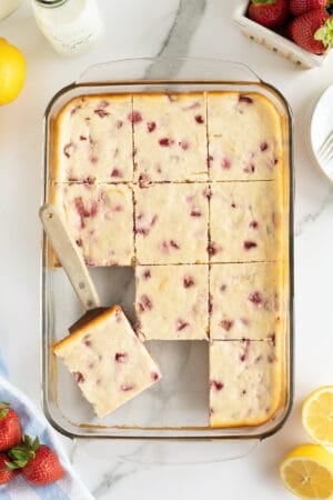 A top down shot of a spatula resting in a baking dish of Strawberry Cheesecake Bars.