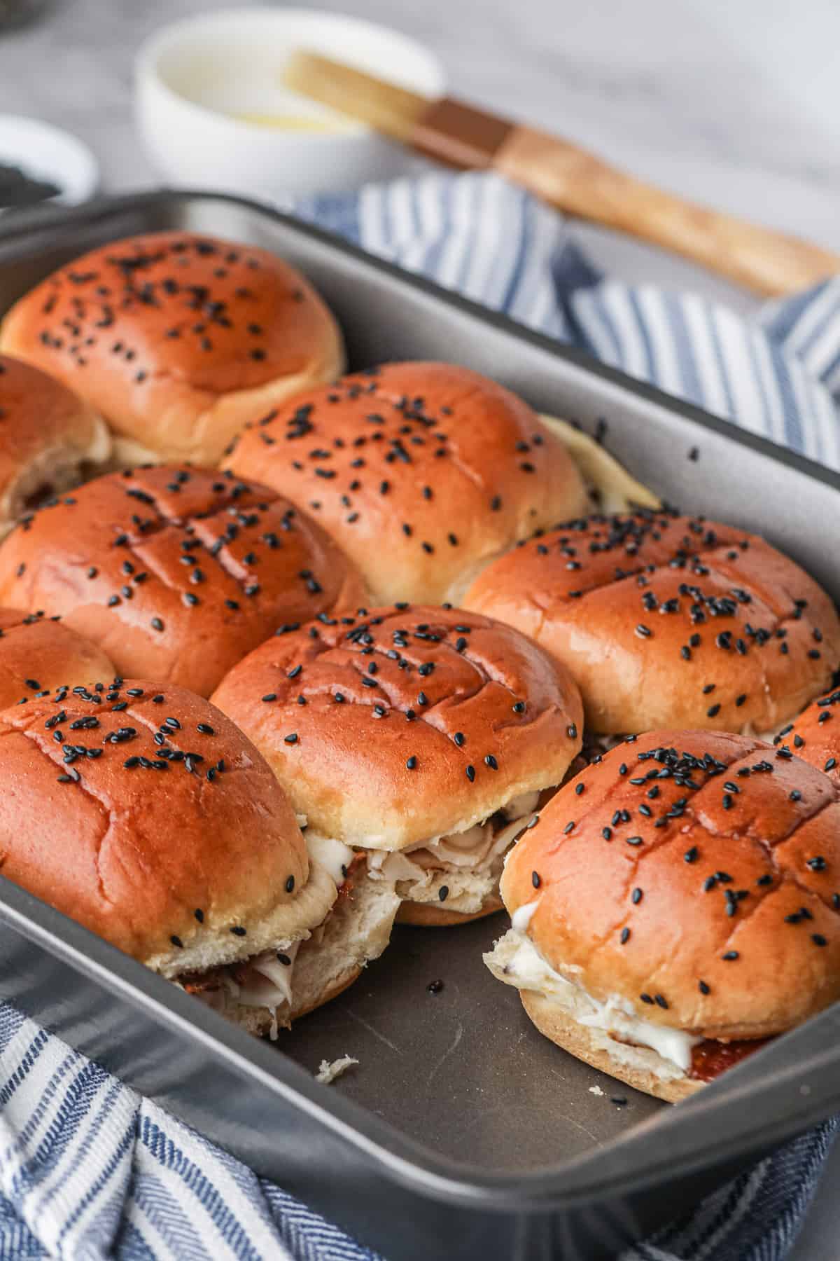 A metal baking pan filled with sliders with one missing.