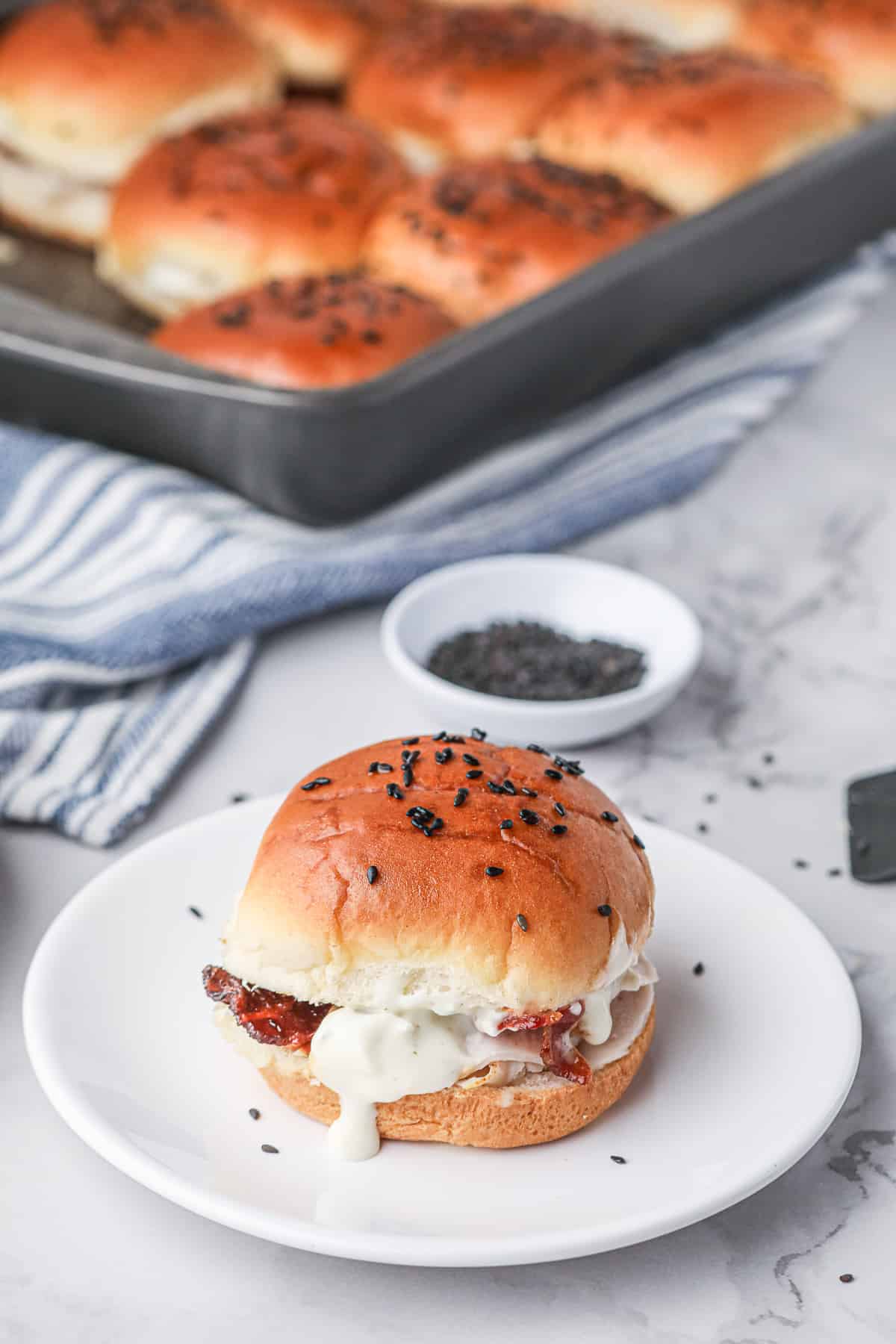 A slider with Ranch dressing oozing out from the middle on a white plate.