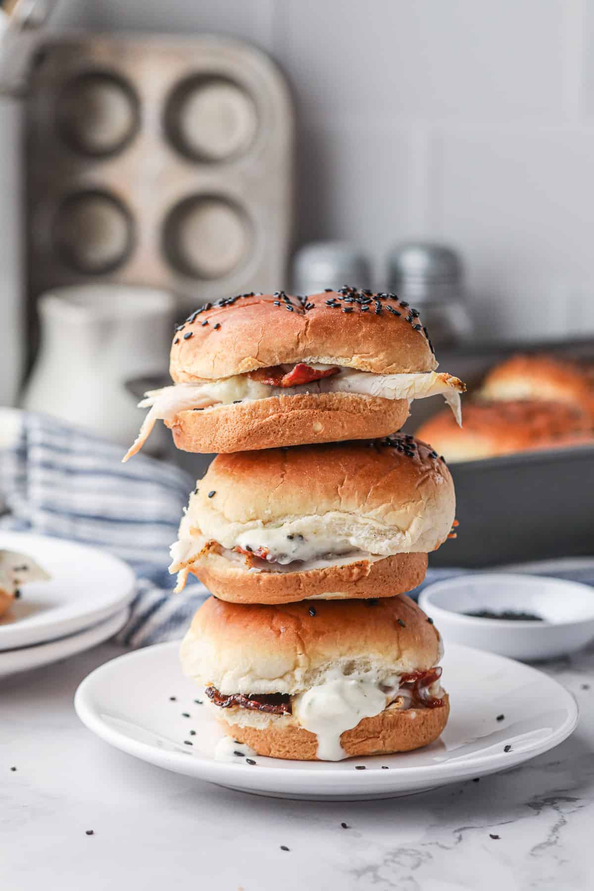 A stack of three Turkey Bacon Ranch Sliders on a white plate.