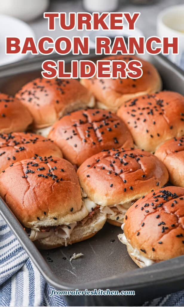 A metal baking pan filled with sliders with one missing with text.