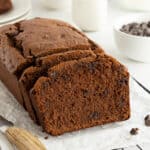 A side view of a sliced loaf of chocolate peanut butter banana bread on a wire rack with a serrated knife.