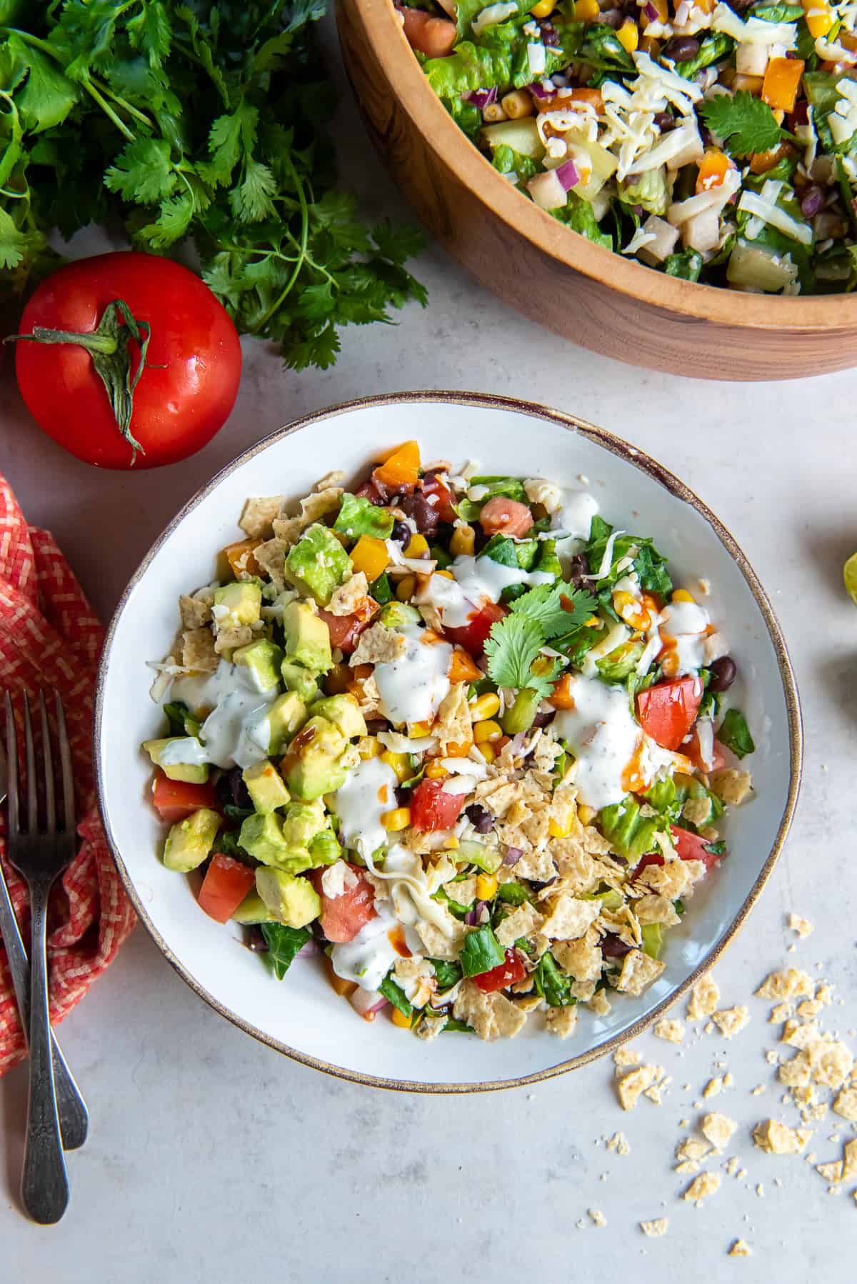 A top down shot of A bowl of southwest chopped salad topped with crushed tortilla chips and a drizzle of jalapeno ranch dressing.