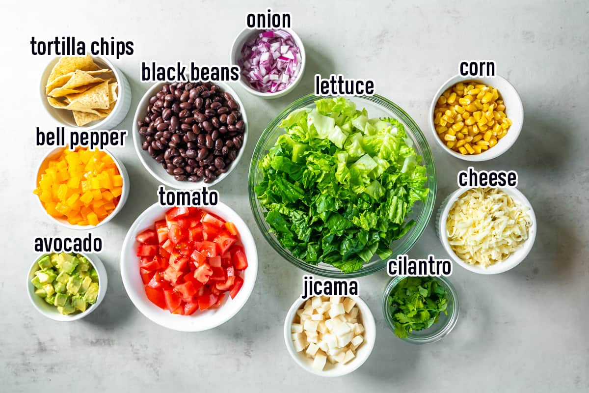Lettuce, tomatoes, black beans, and other ingredients in bowls with text.