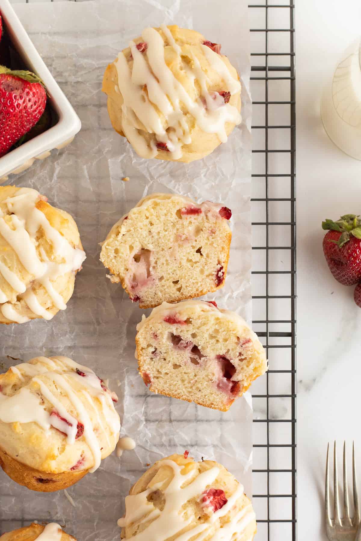 A top shot of strawberry muffins that have been cut in half resting on a wire rack.