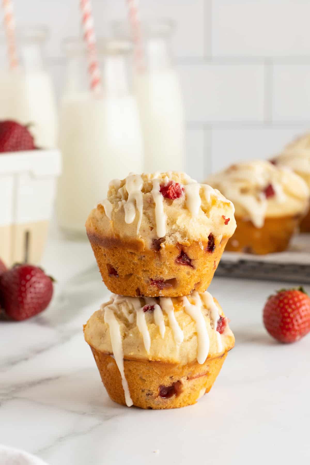 Two strawberry muffins stacked on a kitchen counter.