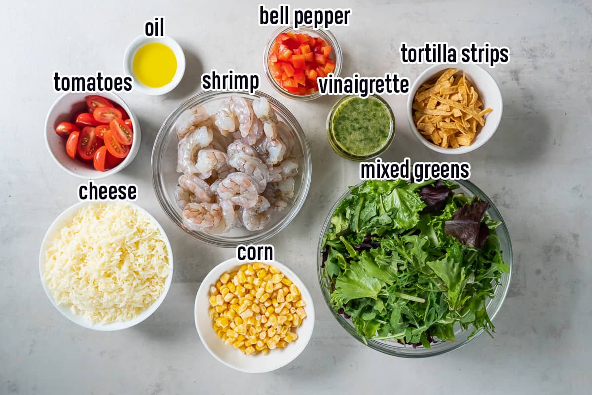 Shrimp, mixed greens, cheese and other ingredients for Cilantro Lime Shrimp Salad in bowls with text.