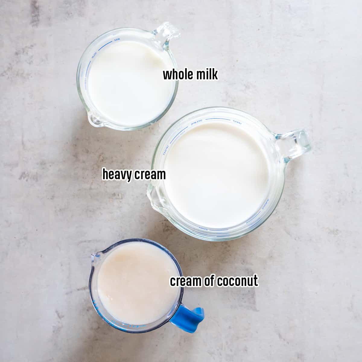 Cream of coconut, whole milk, and heavy cream in glass measuring cups with text.