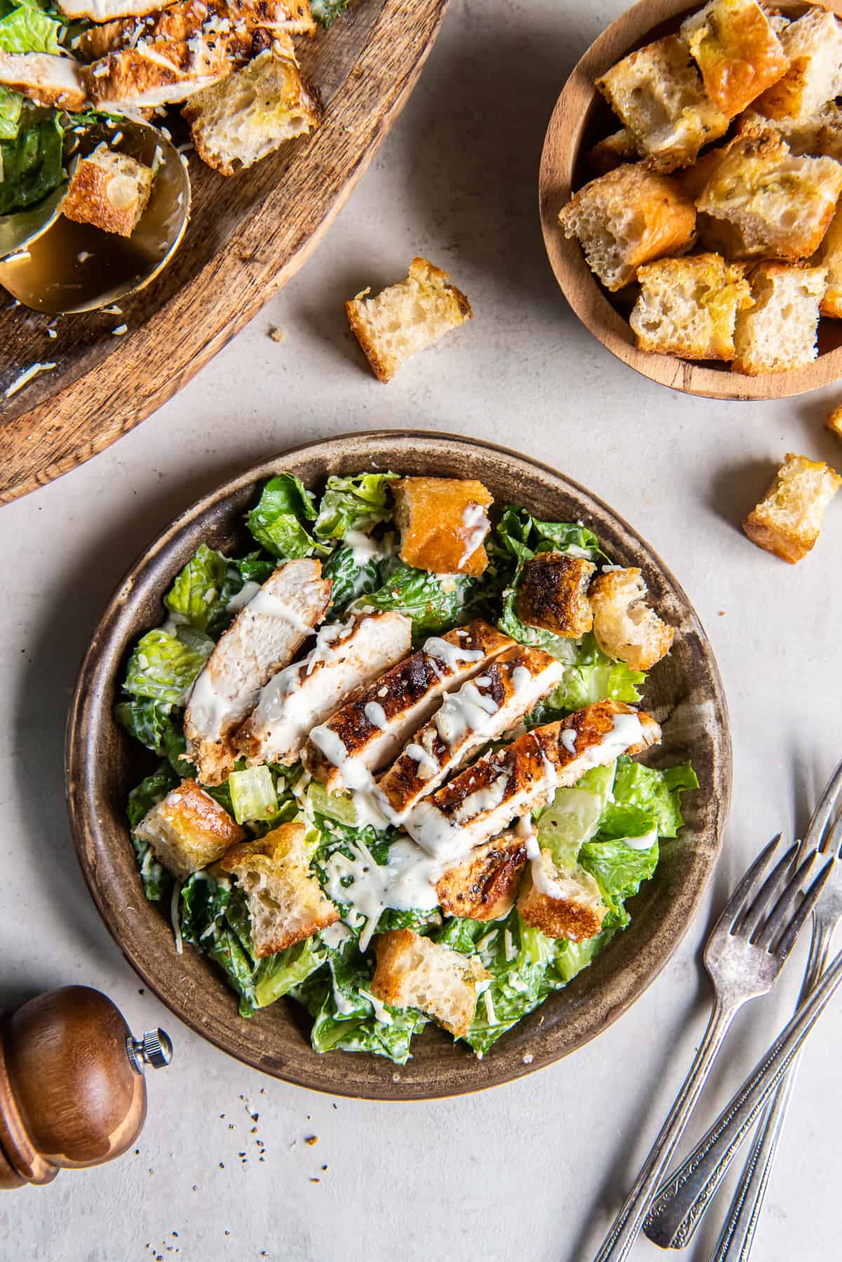 A top down shot of a a serving of grilled chicken Caesar salad with focaccia croutons on a salad plate.