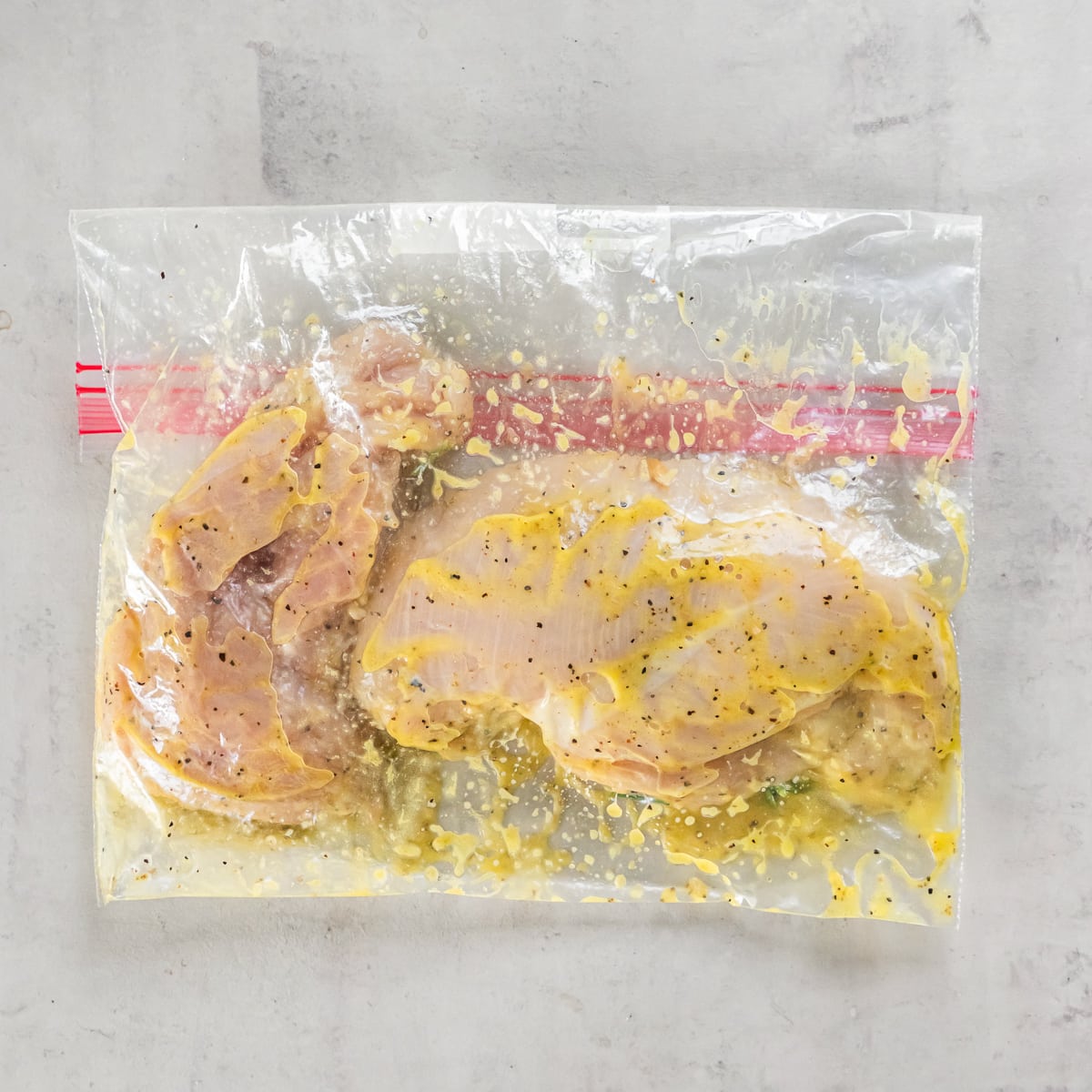 Chicken and marinade in a gallon size zippered plastic storage bag.