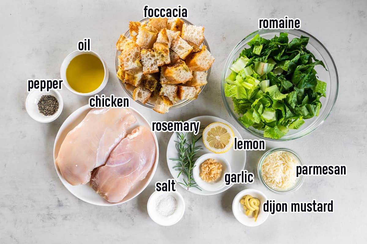 Cubed focaccia, raw chicken breasts, oil, romaine and other ingredients in bowls with text.