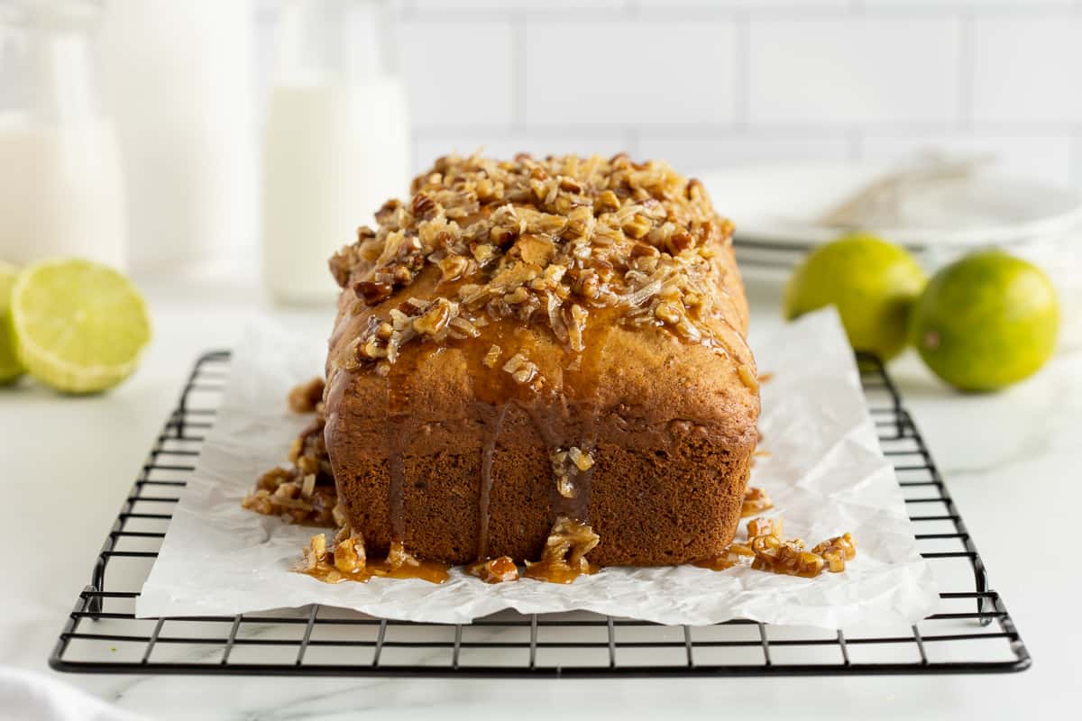 A partially sliced loaf of Jamaican Banana Bread on a piece of parchment paper on a wire rack.