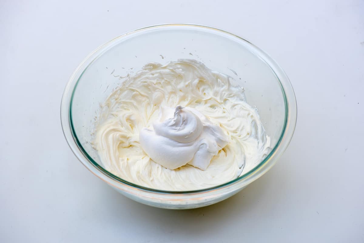Pudding and whipped topping in a glass mixing bowl.