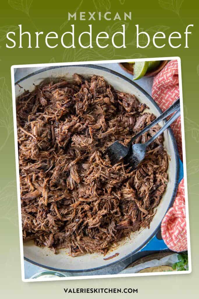 Two forks resting in a pan with Mexican shredded beef with text overlay.