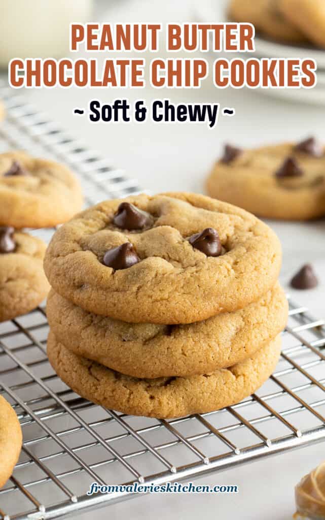 A stack of three peanut butter chocolate chip cookies on a wire rack.