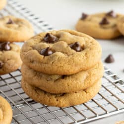 A stack of three peanut butter chocolate chip cookies on a wire rack.