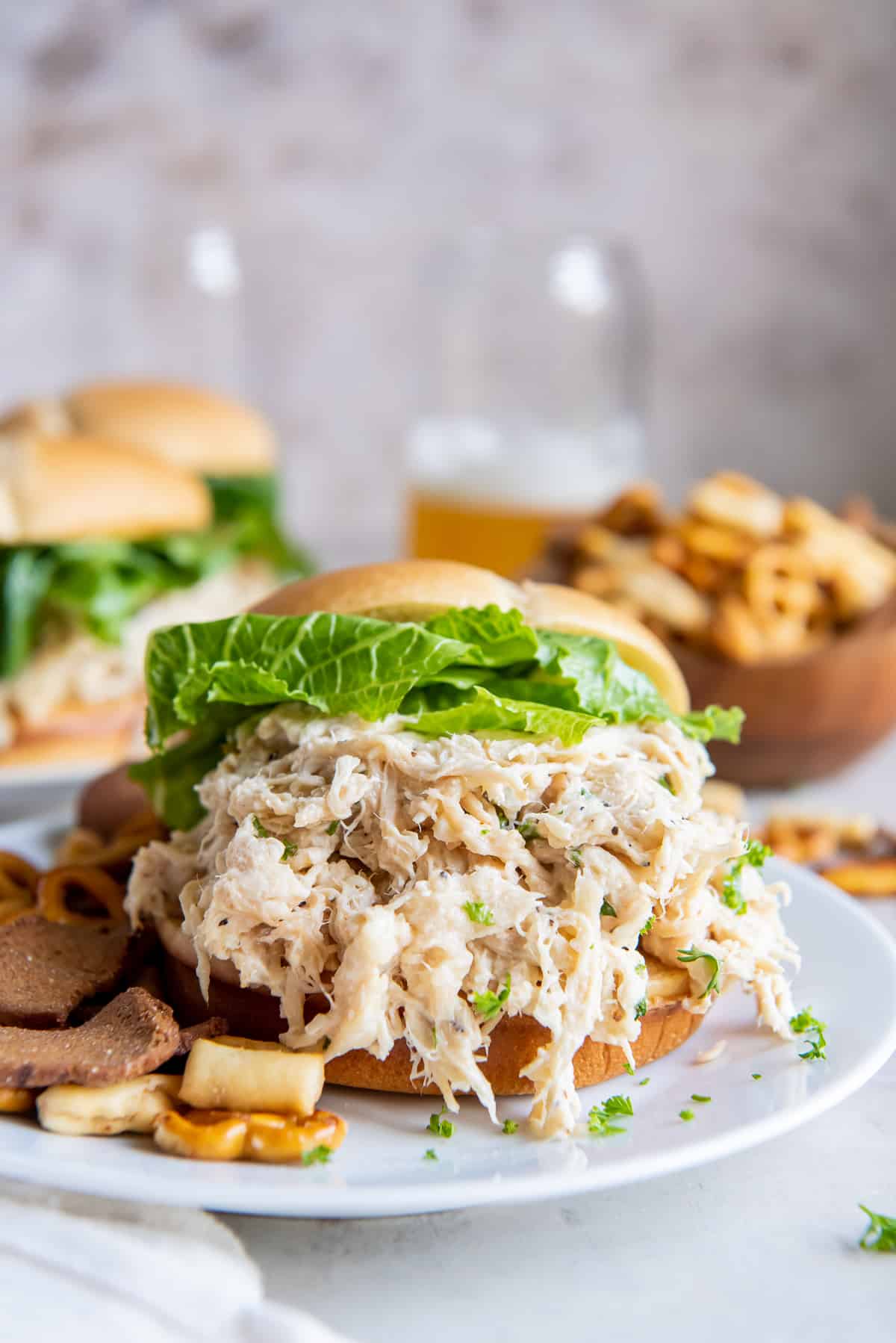 A bun stuffed full with shredded Caesar chicken and romaine lettuce on a white plate.