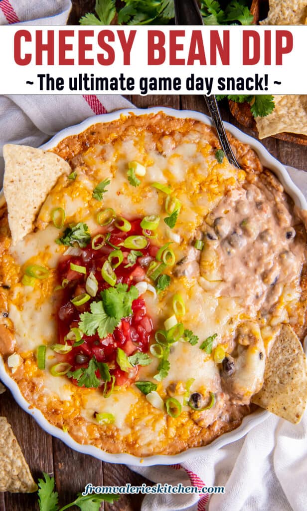 A top down shot of a tortilla chip pressed into bean dip topped with melted cheese, salsa, and green onions with text.