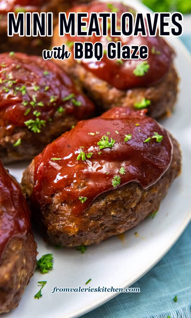 A close up of individual mini meatloaves with glaze on a white platter with text.