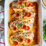 A top down shot of four pieces of stuffed chicken topped with cheese and pepperoni in a baking dish.