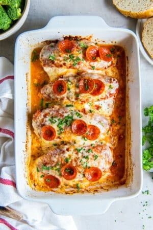 A top down shot of four pieces of stuffed chicken topped with cheese and pepperoni in a baking dish.