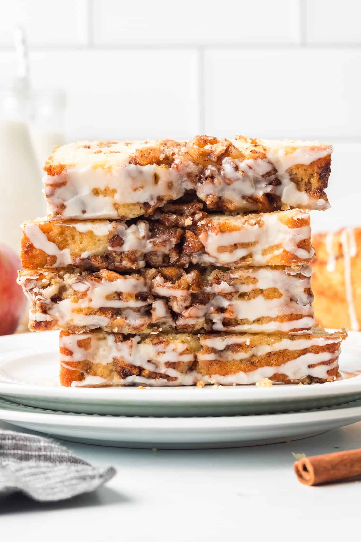 Slices of glazed apple fritter bread stacked on a white plate.