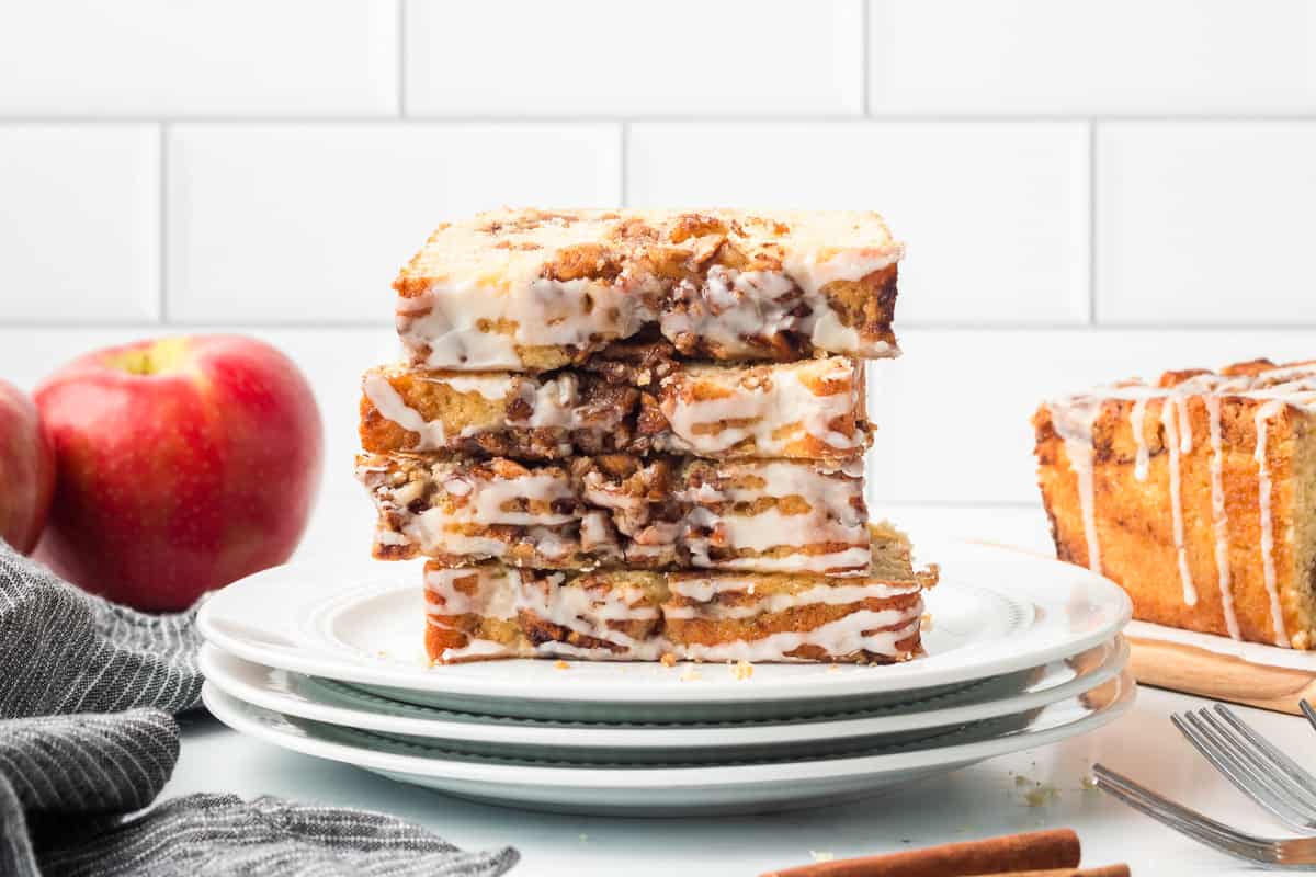 Slices of glazed apple fritter bread stacked on a white plate.